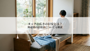 Person sits on a window-side sofa reading a book in a bright, cozy living space with wooden floors and a throw blanket.